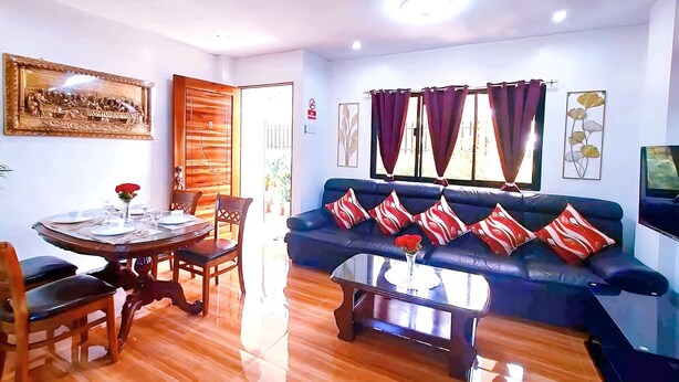 Un salón con sofá, mesa de centro, mesa de comedor, sillas y un cuadro en la pared.
