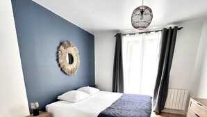 Une chambre moderne avec un lit, une table de chevet en bois et un luminaire fixé au mur.