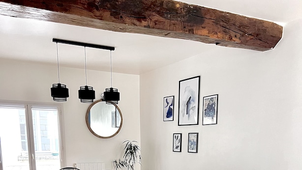 Un salon moderne avec un canapé d’angle gris, une table basse ronde et un coin repas comprenant une table et des chaises en bois.