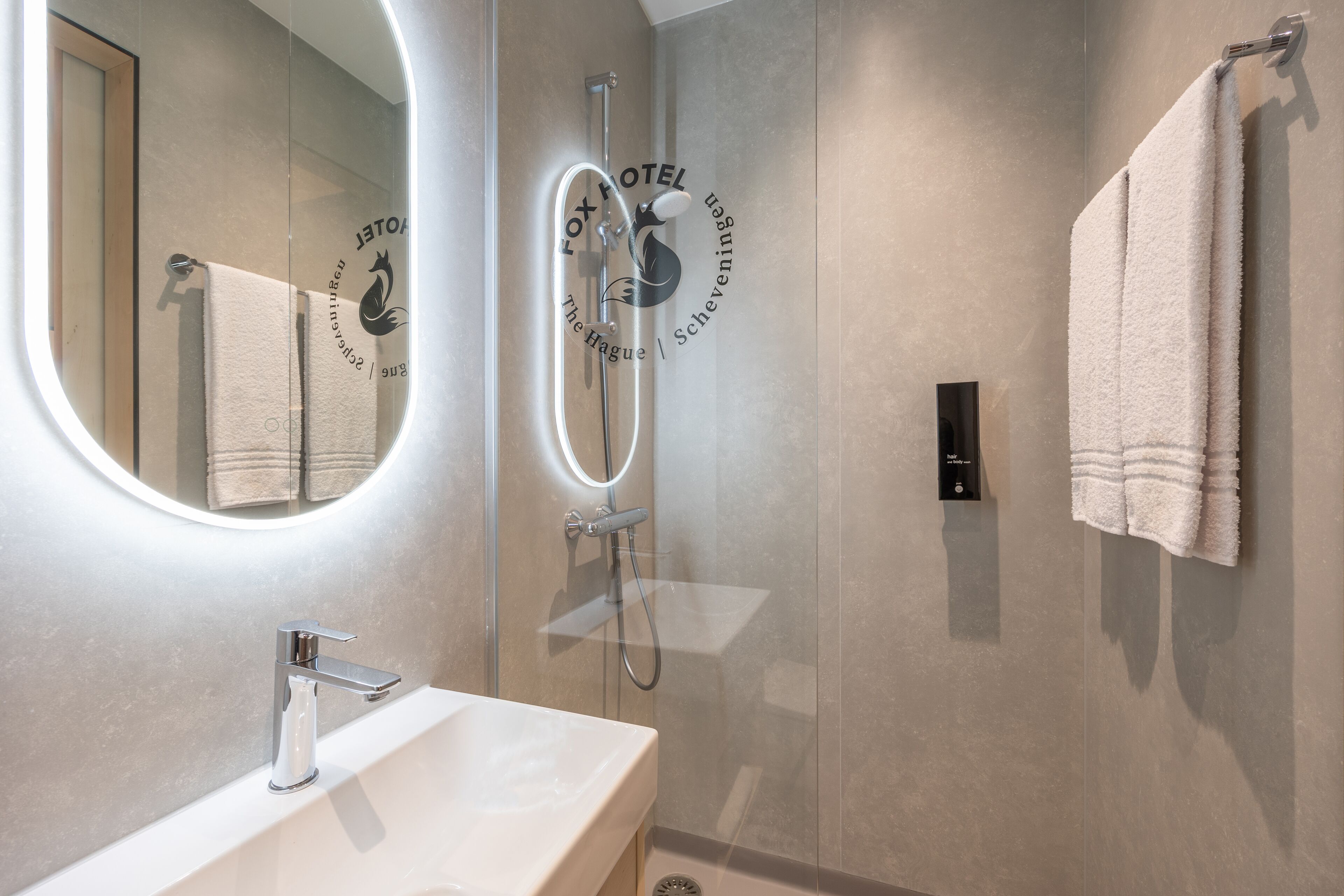 A modern bathroom with a glass-enclosed shower, a white sink, and a towel hanging on the wall.