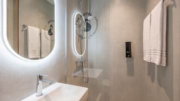 A modern bathroom with a glass-enclosed shower, a white sink, and a towel hanging on the wall.
