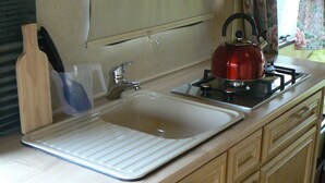 A kitchen with a sink, a kettle, and a plastic container.