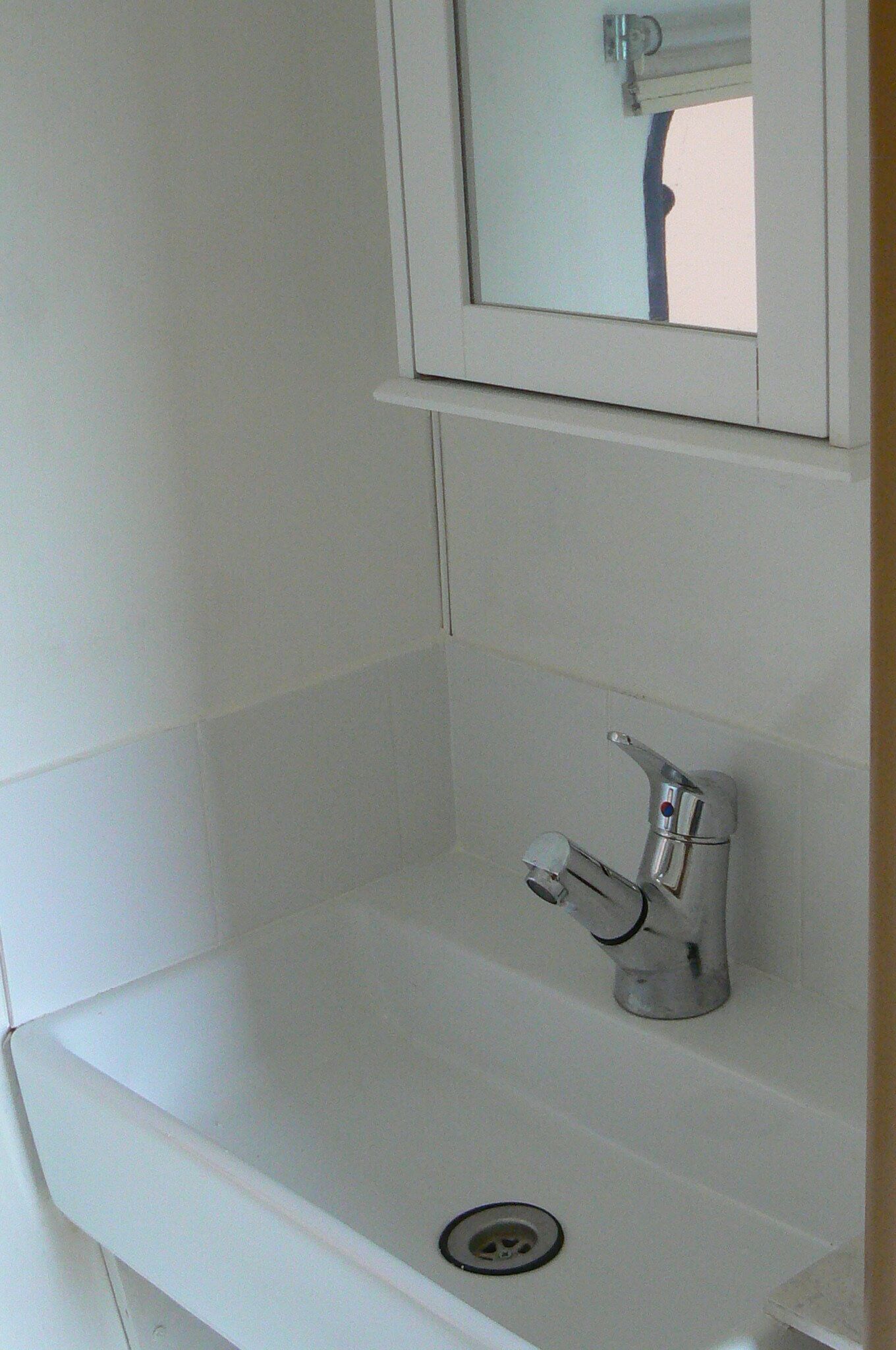 A white bathroom sink with a mirror above it, a faucet, and a drain.