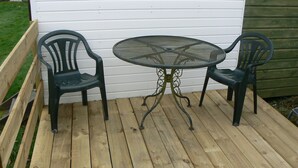 A wooden deck with a round metal table and two chairs.