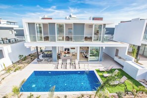 Ein modernes, zweistöckiges Haus mit Schwimmbad, Außenbereich und einem gepflegten Garten.