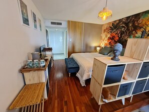 Ein Hotelzimmer mit Bett, Nachttisch, Holzschrank und Schreibtisch mit Stuhl.