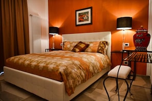 A hotel room with a large bed, two bedside lamps, a desk with a zebra-patterned vase, and a framed picture on the wall.