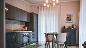 Une cuisine moderne avec un coin repas, comprenant un îlot central, un four encastré et un luminaire suspendu.