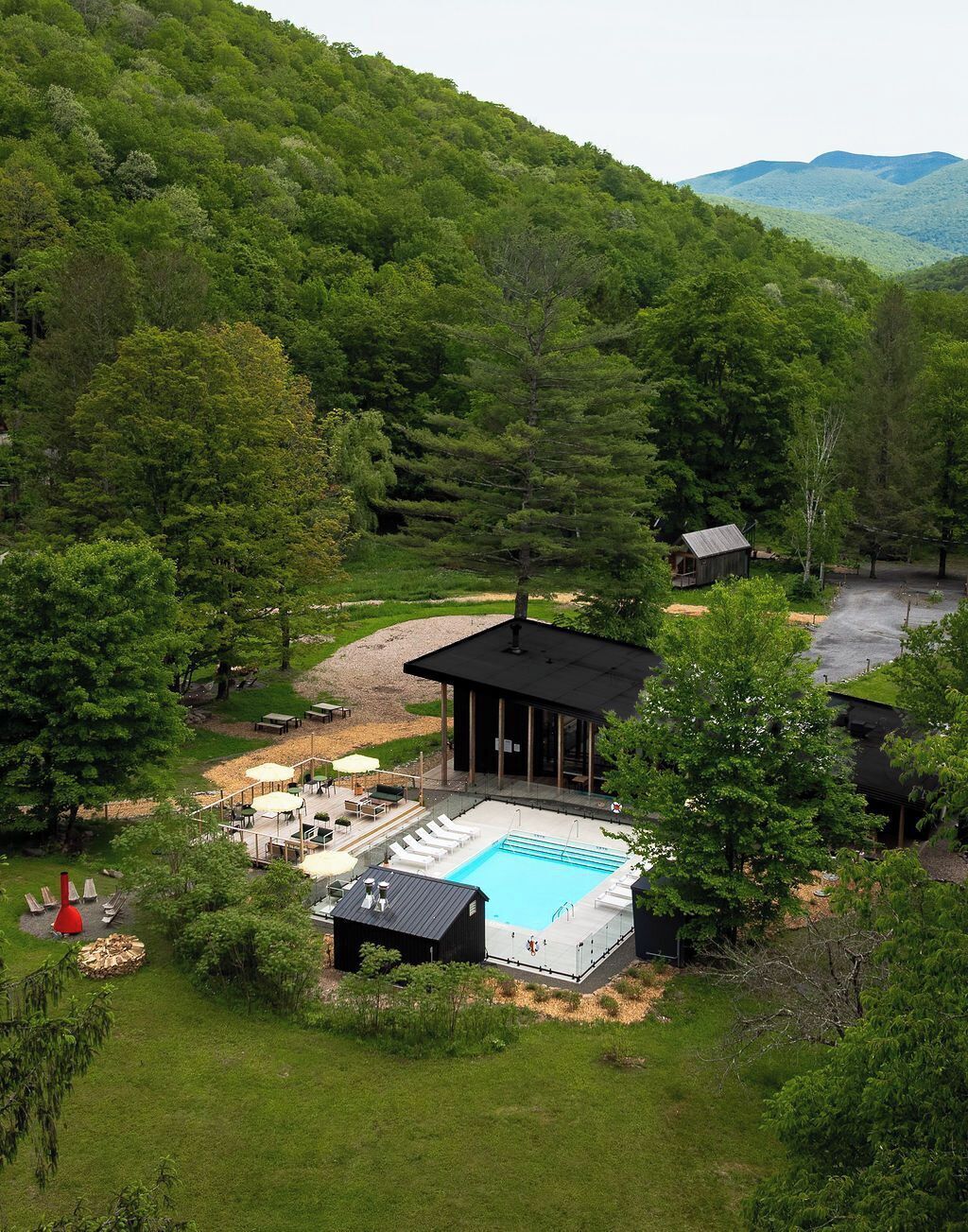En afsidesliggende hytte med swimmingpool, omgivet af frodig vegetation og bjerge.