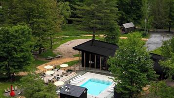 En afsidesliggende hytte med swimmingpool, omgivet af frodig vegetation og bjerge.