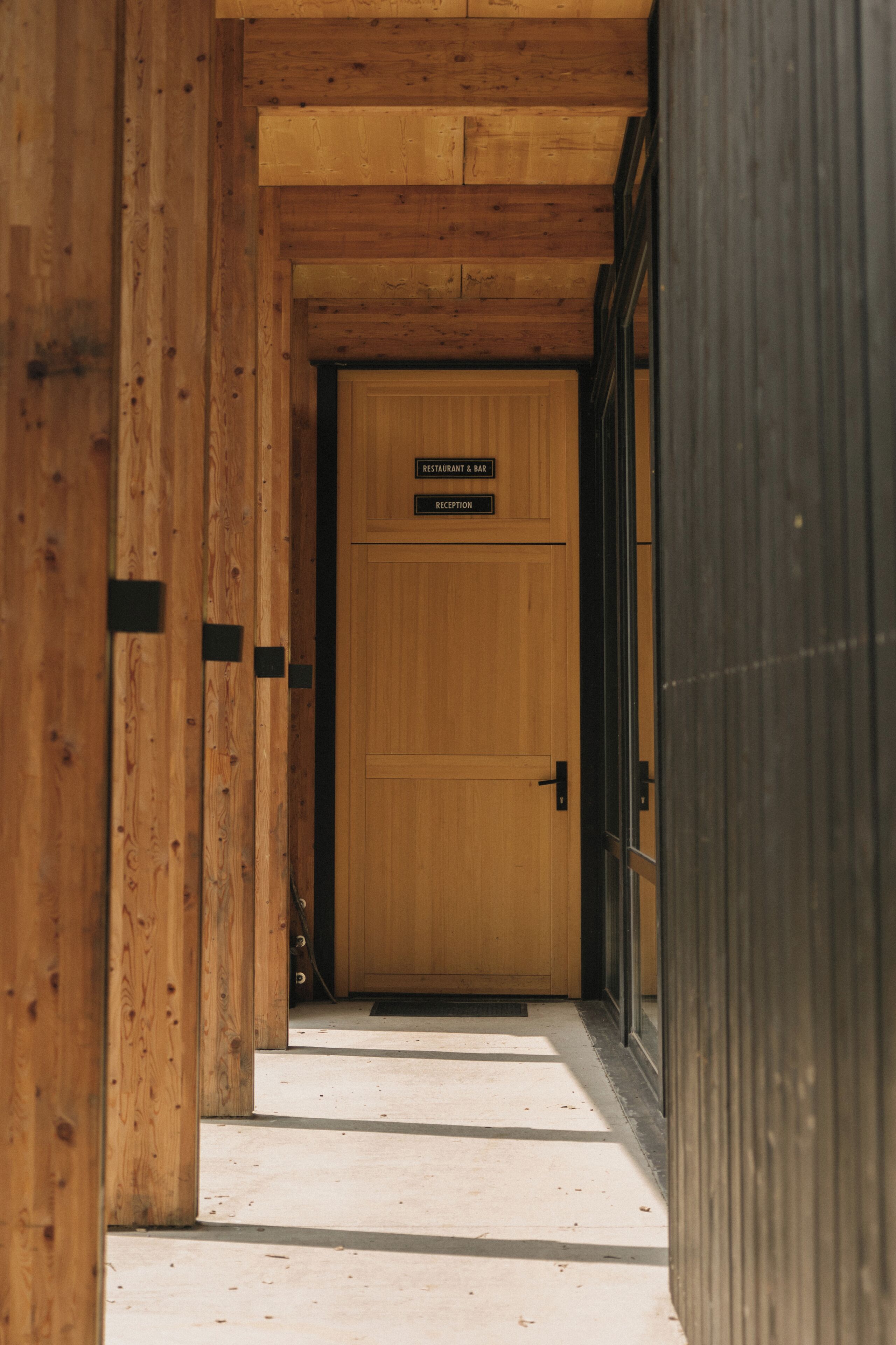 A wooden hallway leading to a reception area with a sign above the door.