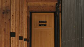 A wooden hallway leading to a reception area with a sign above the door.