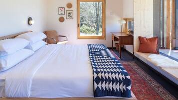 Un dormitorio con cama de madera, un ventanal grande, una mesita de noche y vistas al exterior.