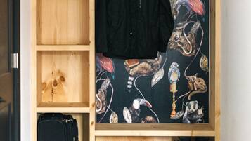 A small room with a wooden wardrobe, a hanging coat rack, a suitcase, and black boots.