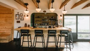 A bar area with wooden beams, a bar counter, and four bar stools. - Eastwind Windham (Windham)