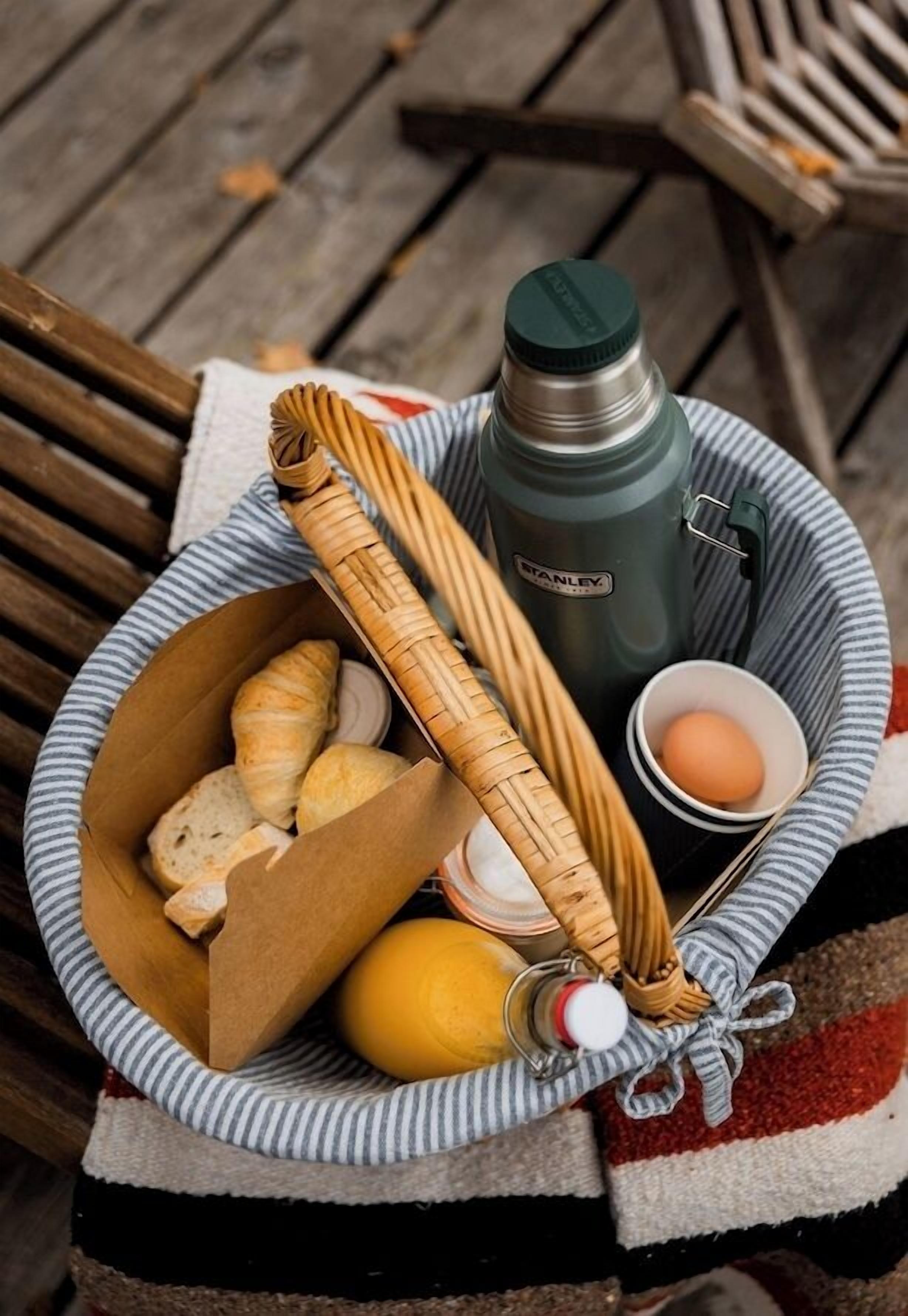 Una cesta con pan, una botella, un limón y una taza.