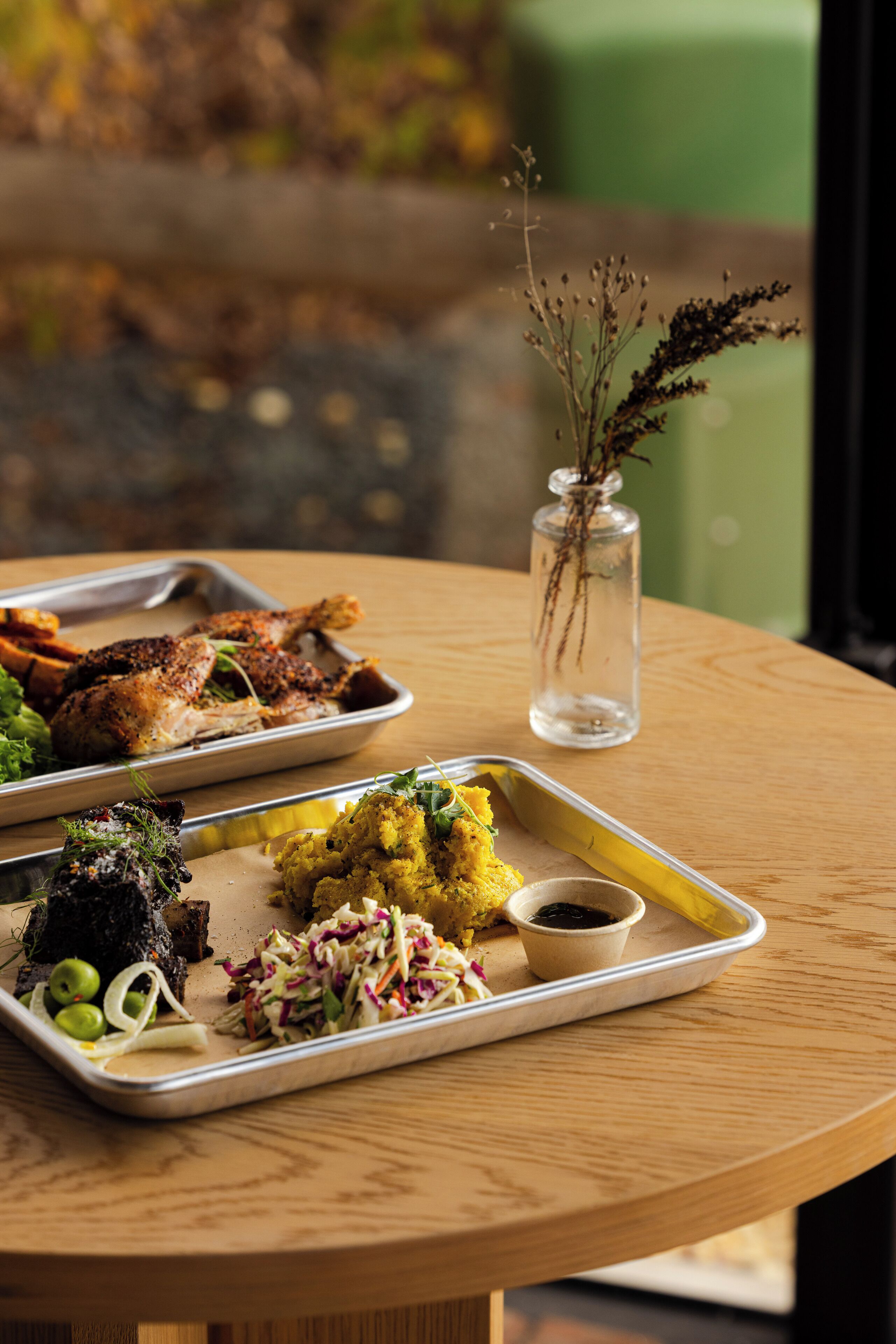 Una mesa con diversos platos, incluyendo pollo asado, ensalada de col y un recipiente pequeño con salsa.
