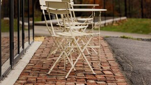 Outdoor seating with a brick pathway and a glass door.