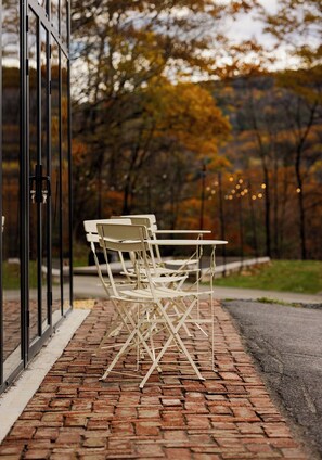 Outdoor seating with a brick pathway and a glass door.