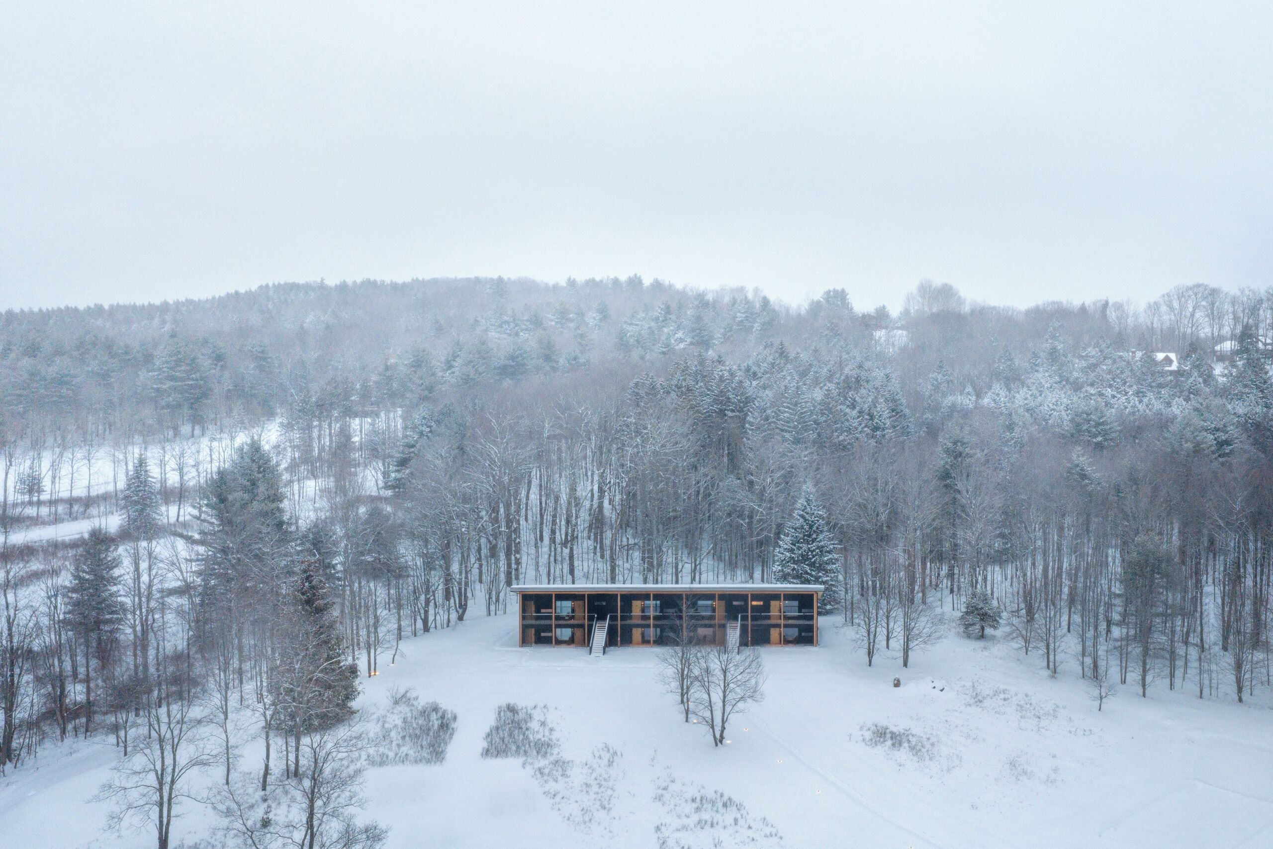 A modern cabin in a snowy forest.