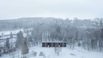A modern cabin in a snowy forest.