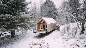 A wooden cabin with a balcony, surrounded by snow-covered trees. - Eastwind Windham (Windham)