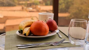 Enjoy a meal with a view at this dining table, set with a fresh fruit platter and comfortable seating.