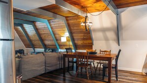 A dining area with a wooden table and chairs, a sofa, and a hanging light fixture. - The Blue Jay A Frame (Jay)