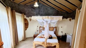 A spacious bedroom with a large bed, a canopy, and a rustic ceiling.