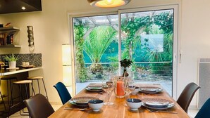 Un coin repas avec une table en bois, dressée pour quatre personnes, entourée de chaises.