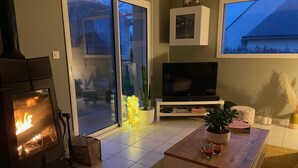 Un salon chaleureux avec une cheminée, un téléviseur et un coin salon confortable.