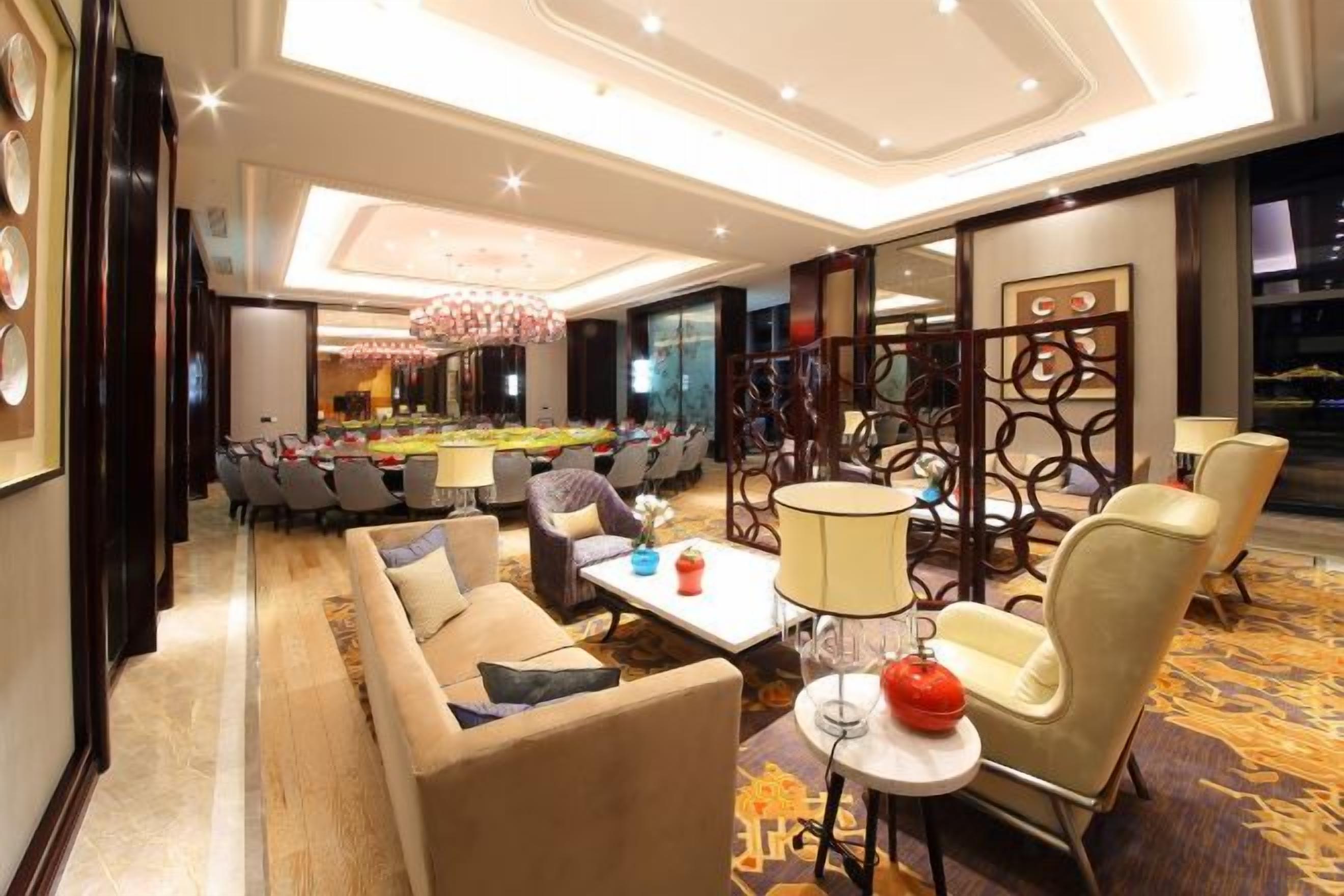 A hotel lobby with a conference table, sofas, and a chandelier.