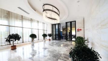 Un'ampia hall con pavimento in marmo, ampie finestre e piante in vaso.