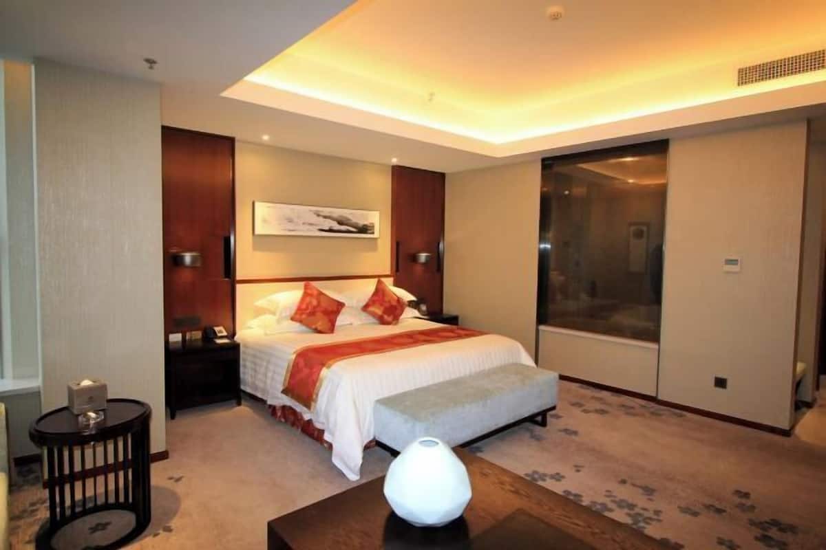A hotel room with a bed, bedside tables, a nightstand, a lamp, a painting on the wall, and a sliding door closet.
