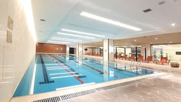 Une piscine avec des couloirs de nage, des chaises longues et un design de plafond moderne.