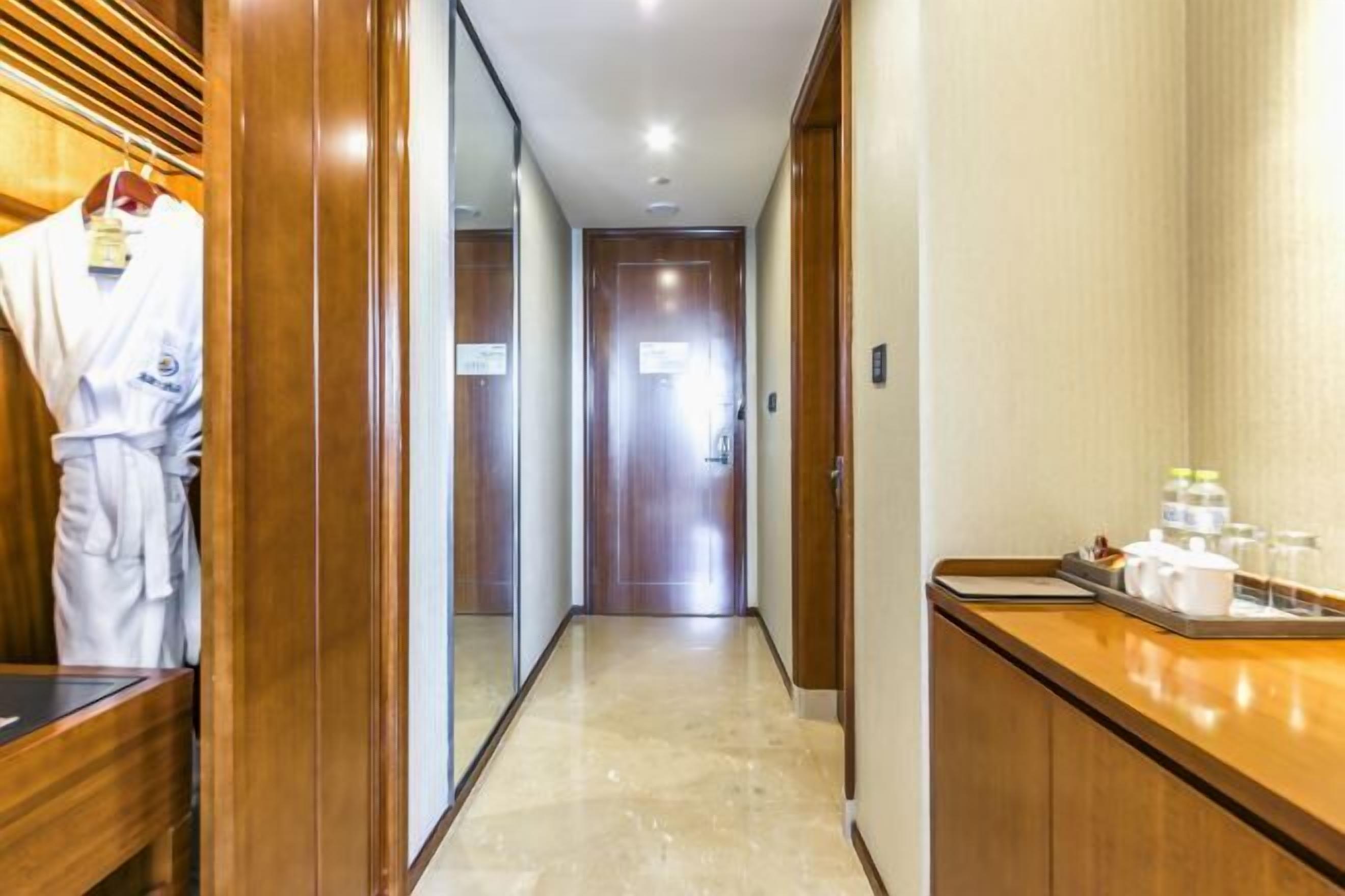 A hotel hallway with wooden paneling, a reception desk with amenities, and a robe hanging on a rack.