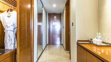 A hotel hallway with wooden paneling, a reception desk with amenities, and a robe hanging on a rack.