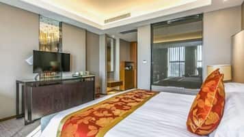 A hotel room with a bed, a TV, a desk, and a large window.