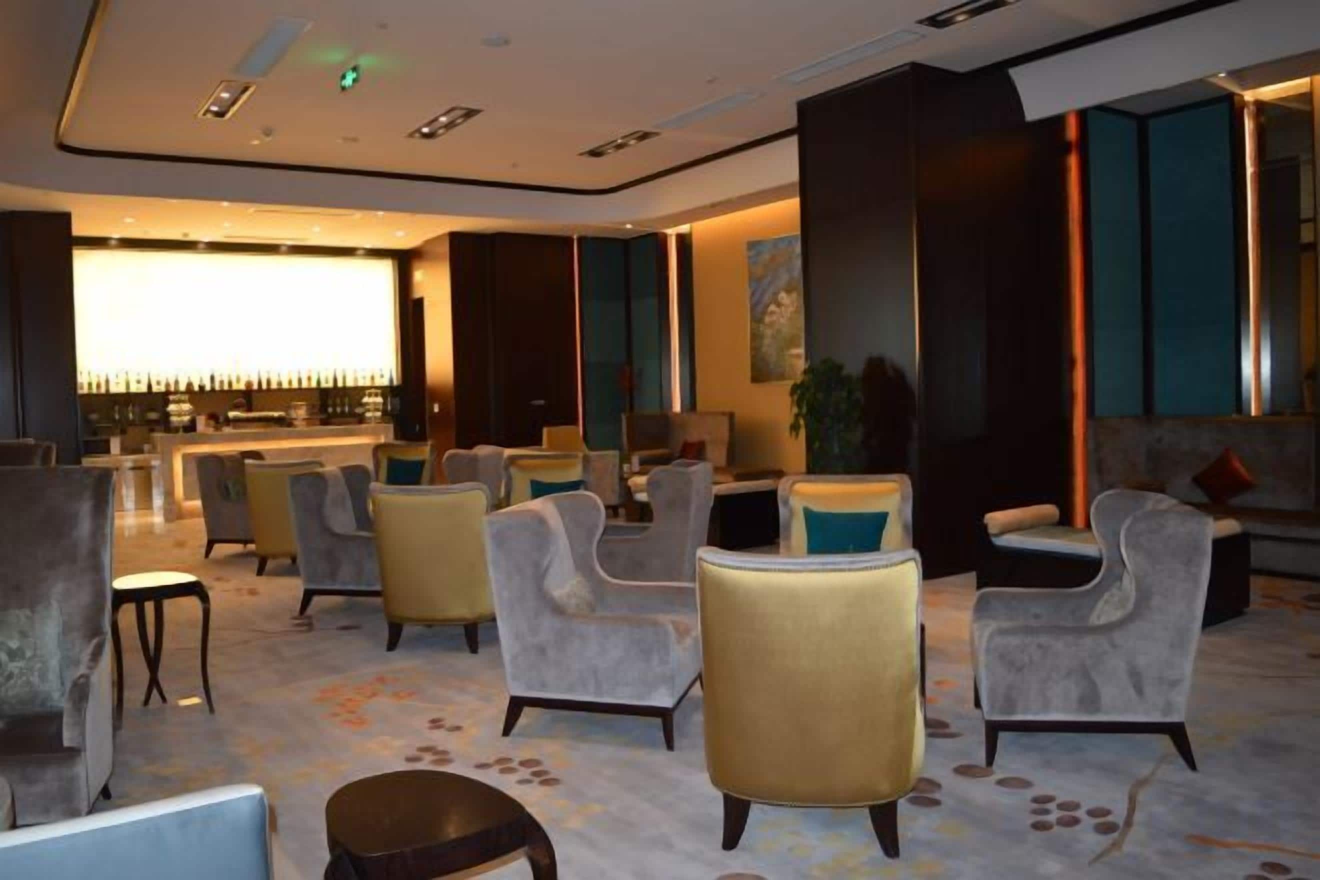 A hotel lobby with seating areas, a bar, and a large window.