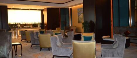 A hotel lobby with seating areas, a bar, and a large window.