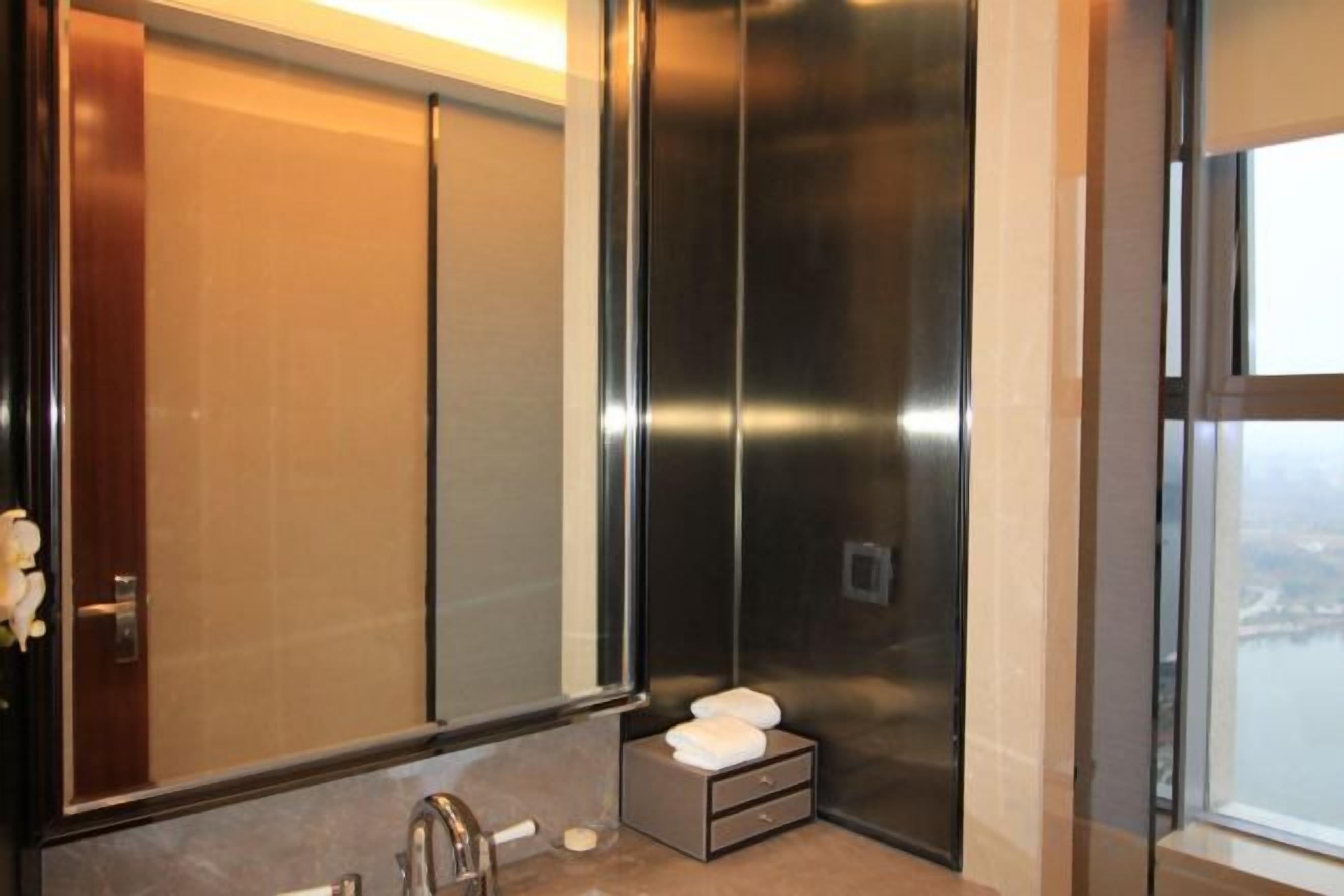 A modern bathroom with a large mirror, a sink, and a small towel rack.