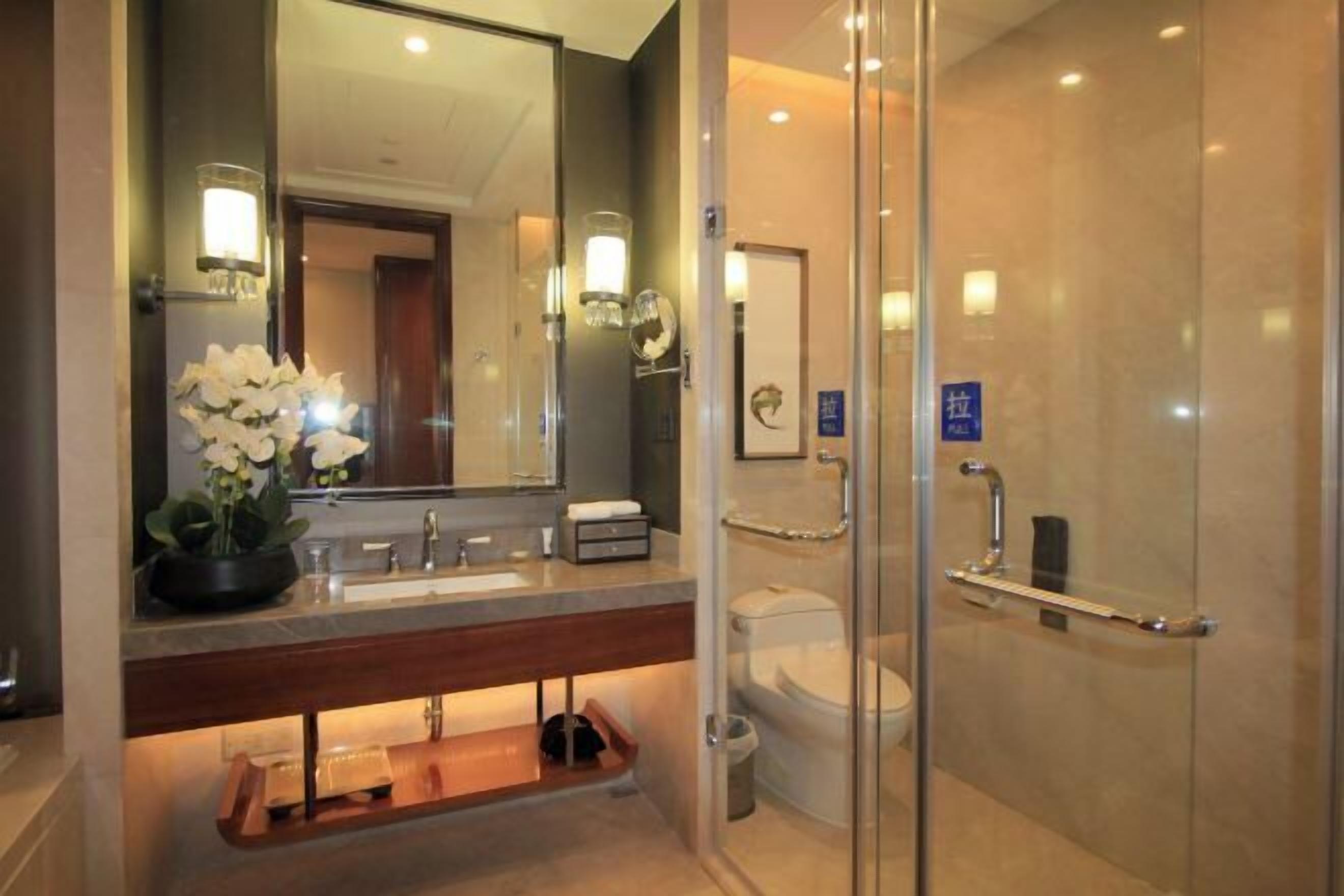 A modern bathroom with a vanity, sink, mirror, and a glass shower enclosure.