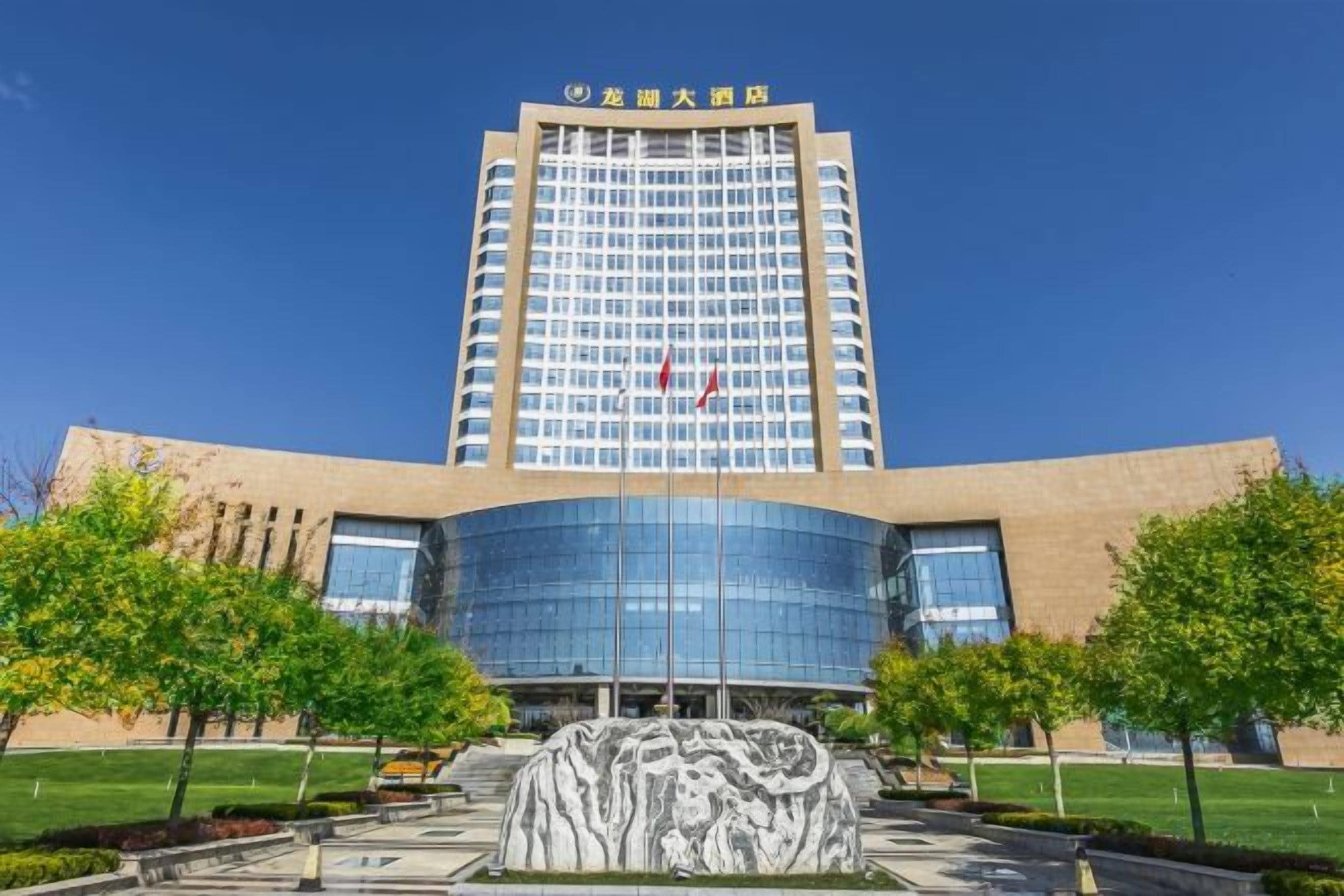 A multi-story hotel with a modern facade, a central entrance, and a landscaped area with a water feature.