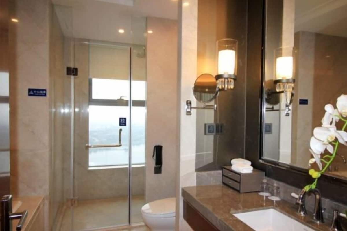 A modern bathroom with a glass-enclosed shower, a large mirror, and a sink with a marble countertop.