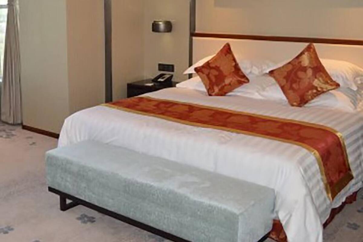 A hotel room with a large bed, a bedside table, and a nightstand.