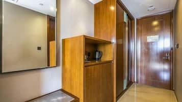A hallway with a wooden cabinet, a mirror, and a door.