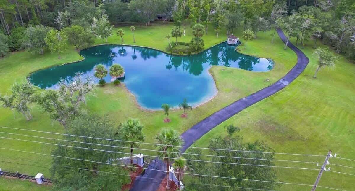 A large pond with a winding path, surrounded by lush greenery and trees.