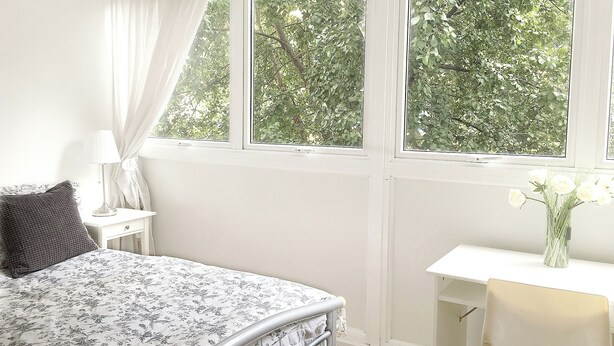 Une chambre à coucher avec un lit, un bureau et une fenêtre donnant sur des arbres.