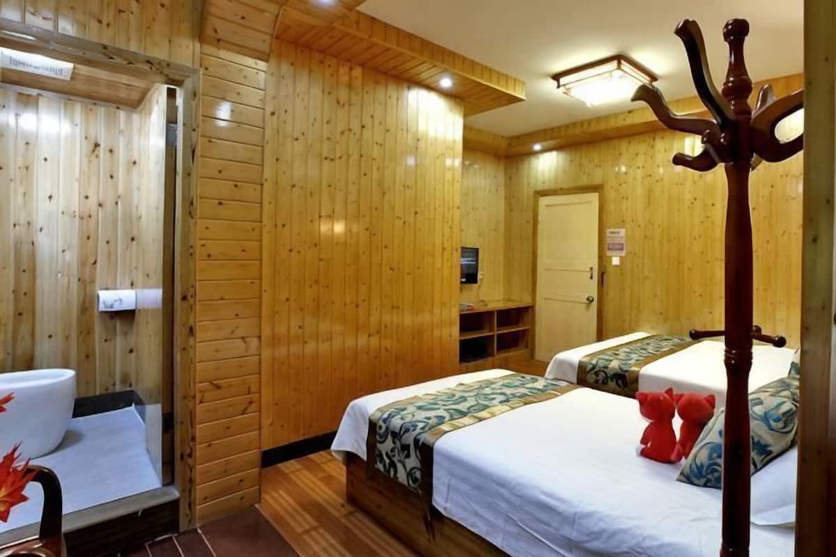 A wooden-paneled room with two beds, a coat rack, and a mirror.