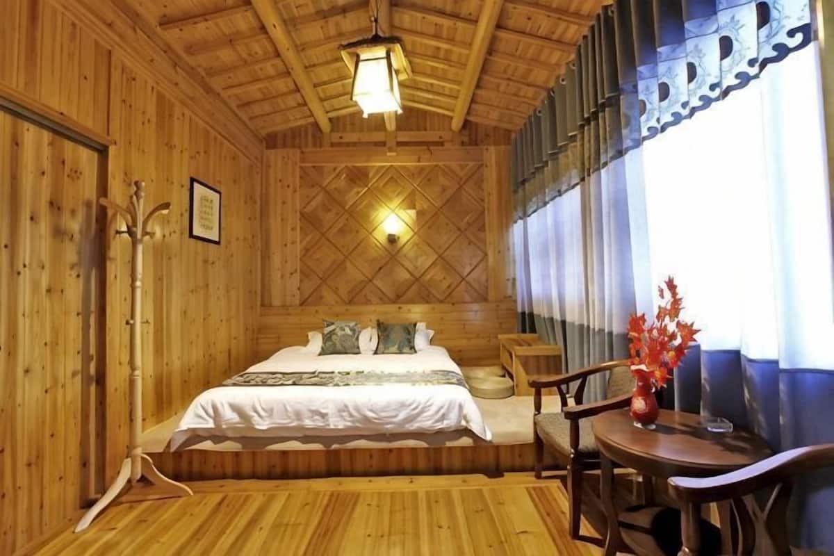 A wooden room with a bed, a table, and a chair.